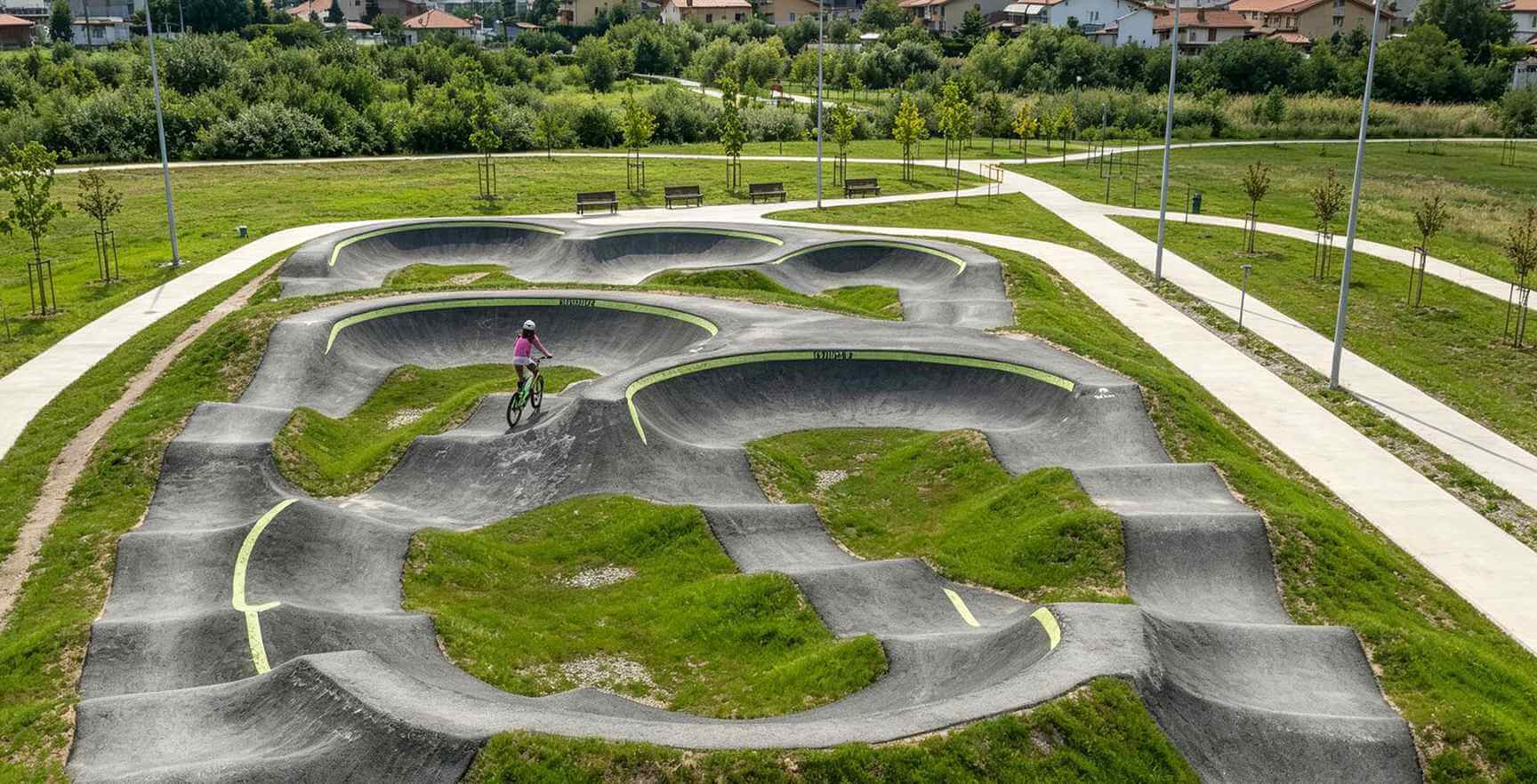 Cyclist Riding an Asphalt Pump Track in a Landscaped Park